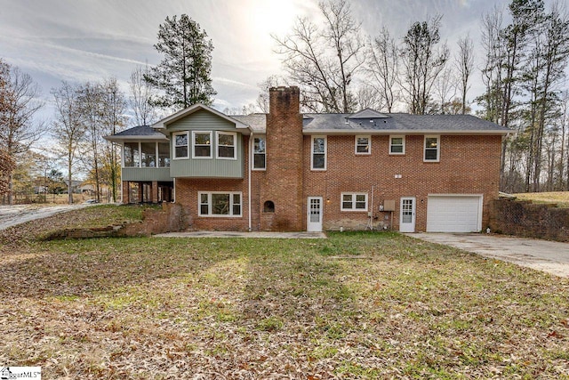 rear view of house with a lawn, a sunroom, and a garage