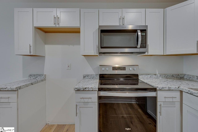 kitchen featuring white cabinetry, light hardwood / wood-style flooring, light stone countertops, and appliances with stainless steel finishes