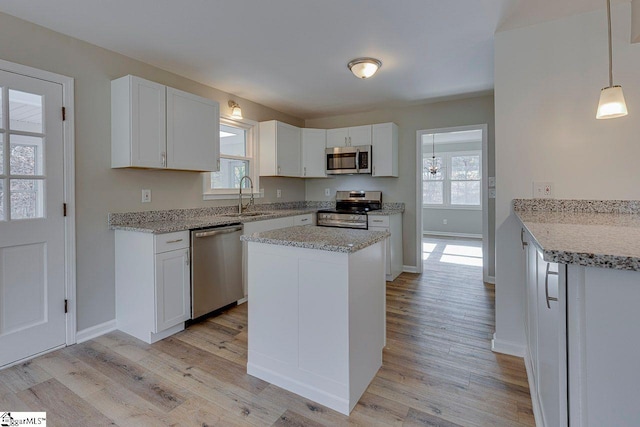 kitchen featuring plenty of natural light, white cabinetry, hanging light fixtures, and appliances with stainless steel finishes