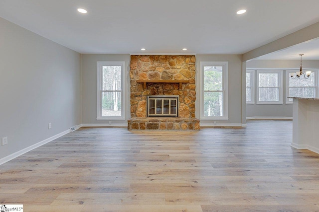 unfurnished living room with a healthy amount of sunlight, a stone fireplace, and light hardwood / wood-style floors