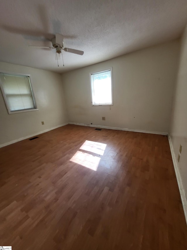 empty room with a textured ceiling, ceiling fan, and dark wood-type flooring