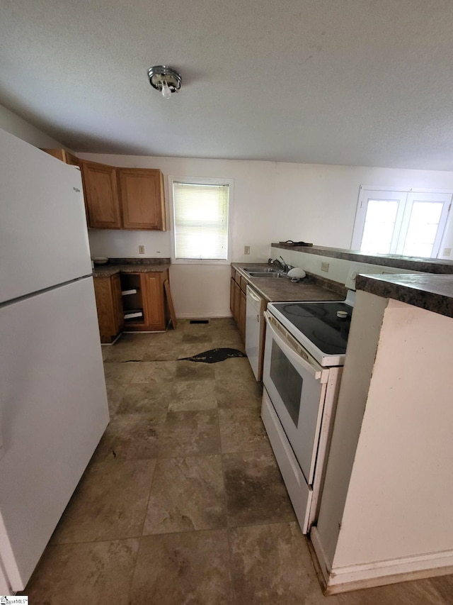 kitchen with a textured ceiling, white appliances, and sink