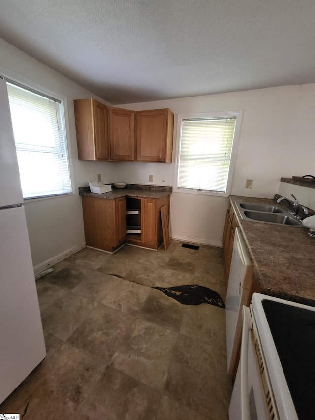 kitchen featuring a textured ceiling, sink, and white appliances