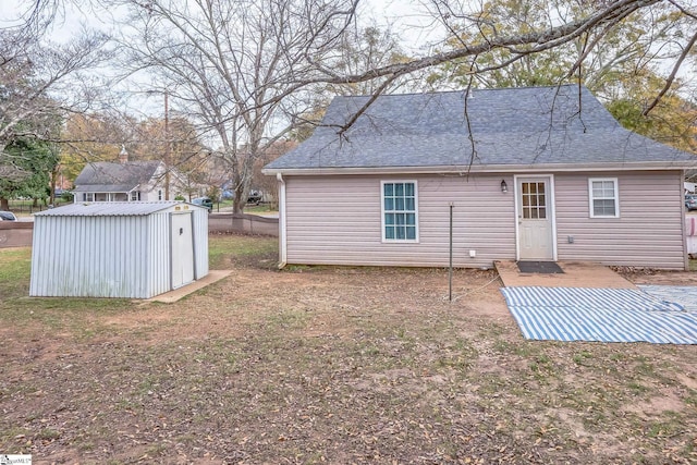 rear view of house with a storage unit and a yard