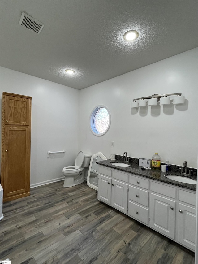 bathroom featuring vanity, hardwood / wood-style floors, a textured ceiling, and toilet