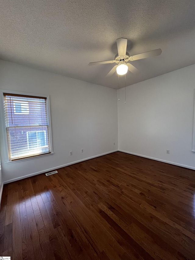 spare room featuring ceiling fan, dark wood-type flooring, and a textured ceiling