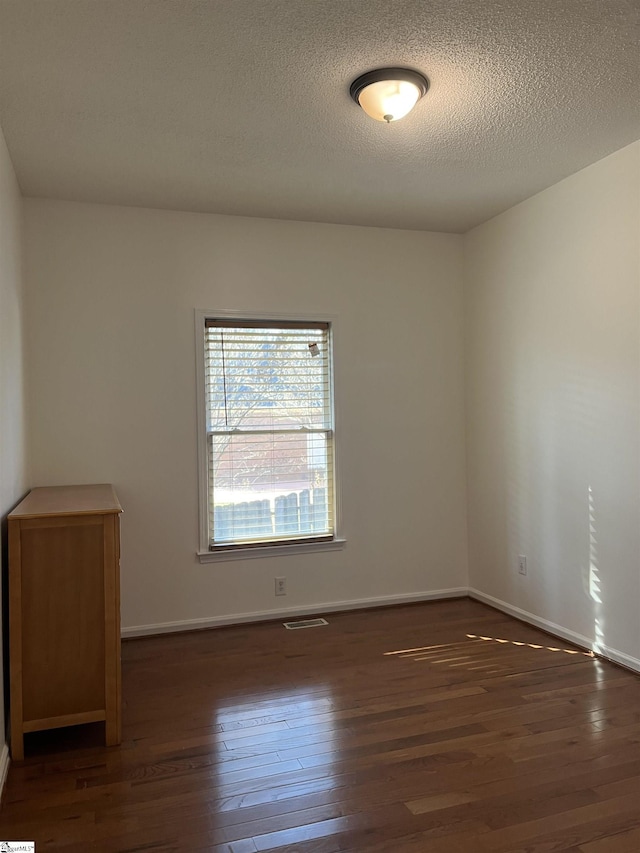 unfurnished room featuring dark hardwood / wood-style floors and a textured ceiling