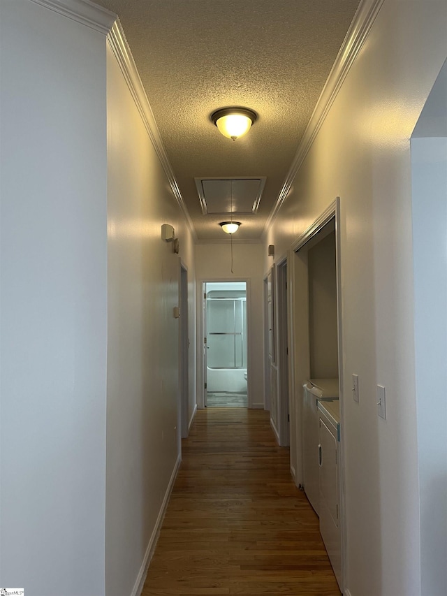 corridor with wood-type flooring, a textured ceiling, washer / clothes dryer, and ornamental molding