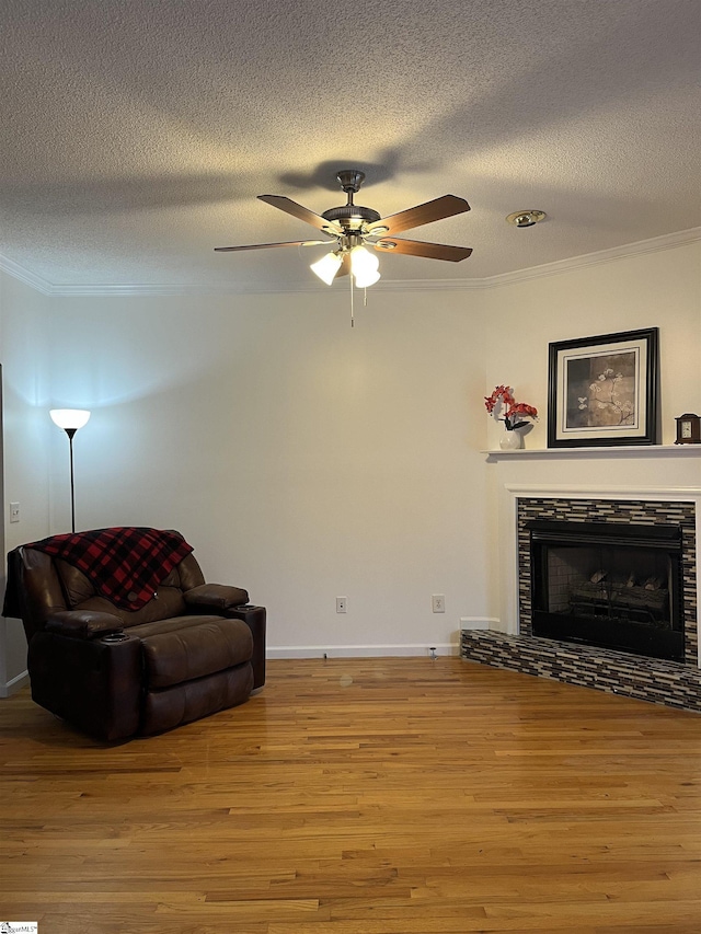 sitting room featuring light hardwood / wood-style floors, crown molding, and a tiled fireplace