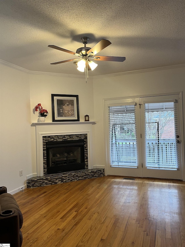 unfurnished living room featuring a textured ceiling, ceiling fan, crown molding, hardwood / wood-style flooring, and a fireplace