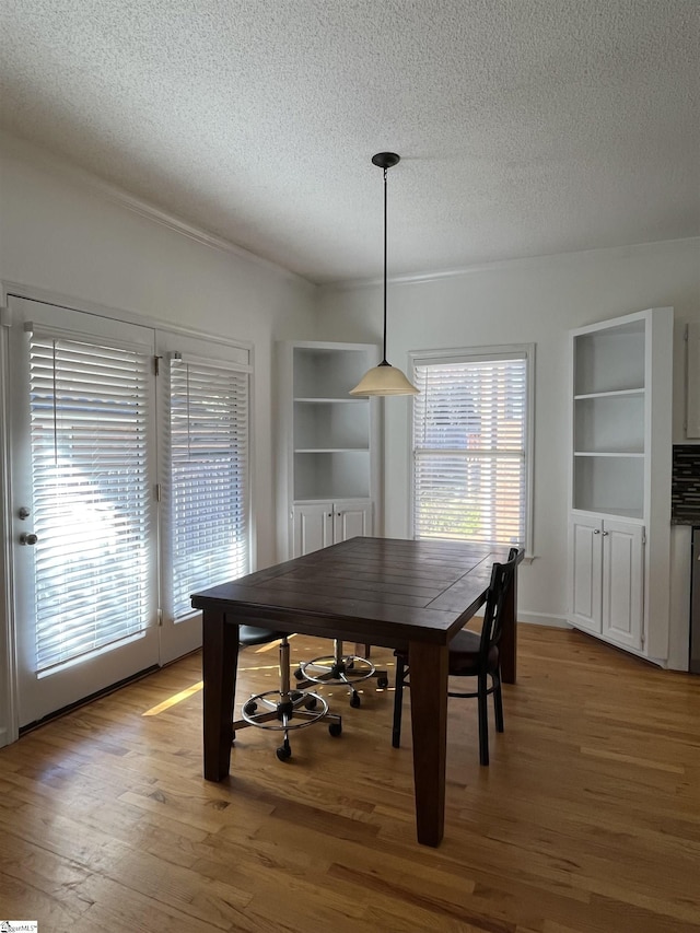 dining area with hardwood / wood-style floors, built in features, and a textured ceiling