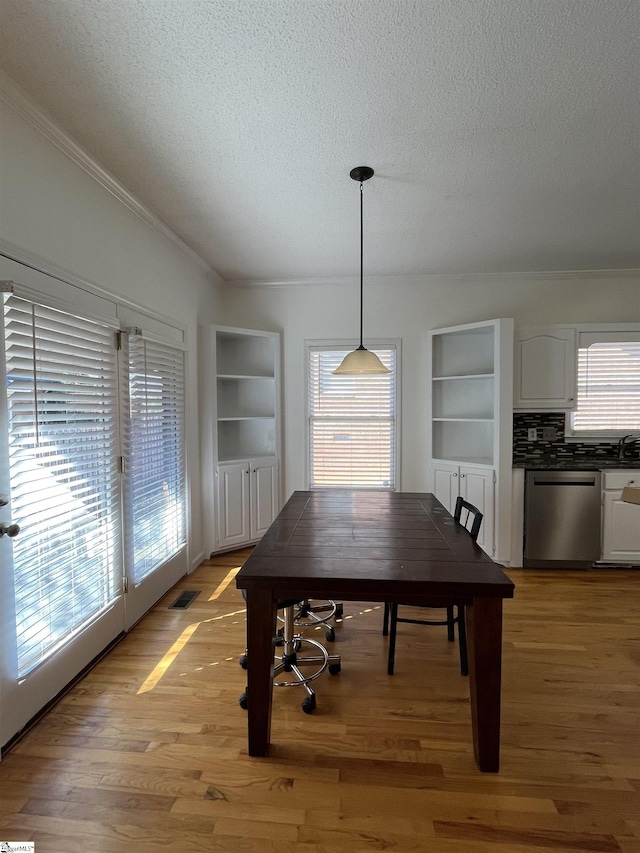 unfurnished dining area featuring plenty of natural light, built in features, a textured ceiling, and light hardwood / wood-style flooring