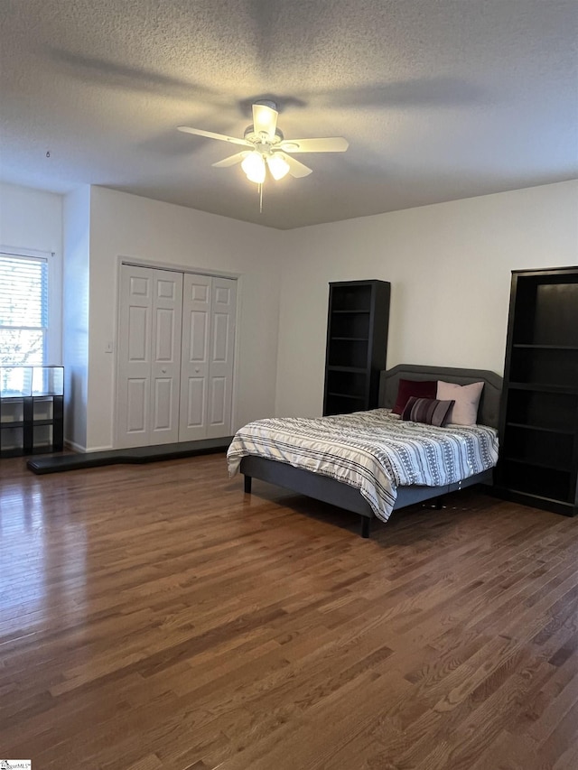 bedroom with ceiling fan, dark hardwood / wood-style floors, a textured ceiling, and a closet