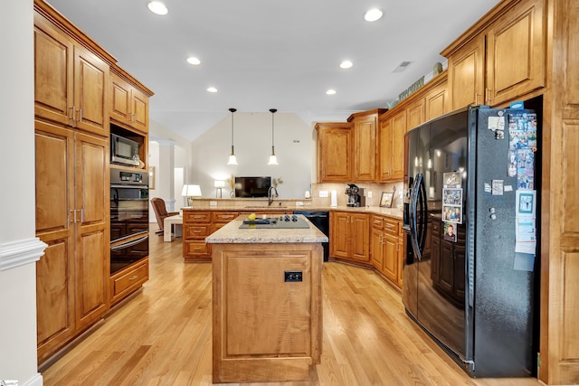 kitchen featuring kitchen peninsula, black appliances, decorative light fixtures, and light wood-type flooring