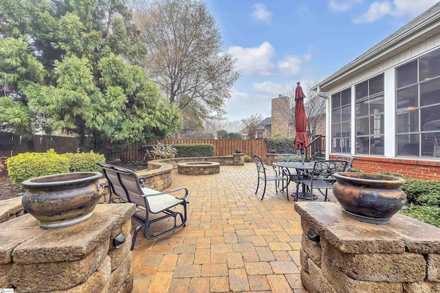 view of patio with a sunroom and an outdoor fire pit