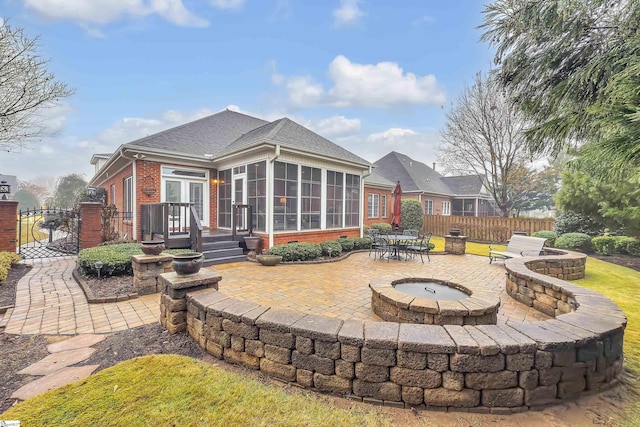 rear view of house featuring a patio area, a sunroom, and an outdoor fire pit