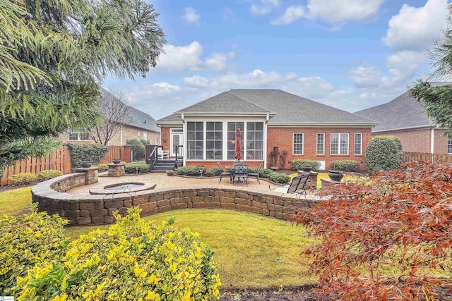 rear view of property featuring a lawn, a sunroom, and a patio