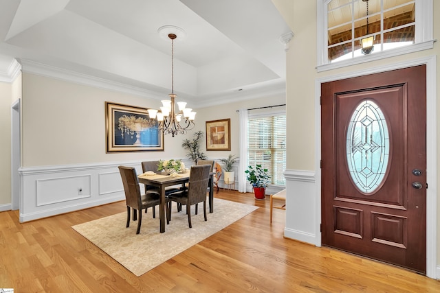 dining space featuring a chandelier, light hardwood / wood-style flooring, a raised ceiling, and ornamental molding