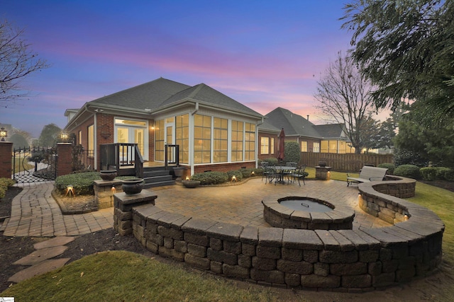 patio terrace at dusk with a fire pit and a sunroom