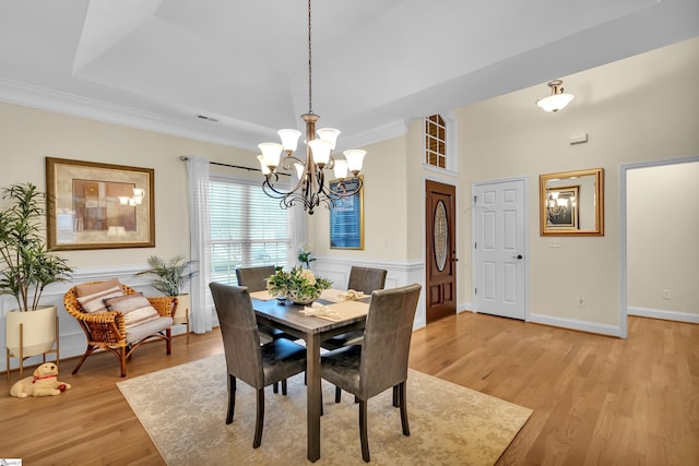 dining room with light wood-type flooring, an inviting chandelier, and crown molding