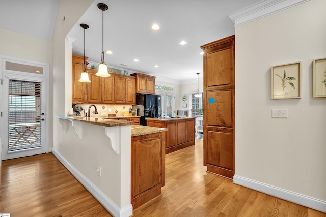 kitchen featuring black refrigerator with ice dispenser, plenty of natural light, and decorative light fixtures