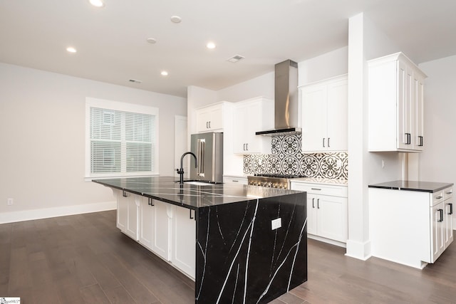 kitchen featuring white cabinets, dark hardwood / wood-style flooring, a center island with sink, and wall chimney range hood