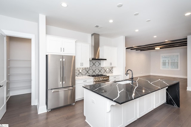 kitchen with high end appliances, sink, wall chimney exhaust hood, dark hardwood / wood-style floors, and white cabinetry