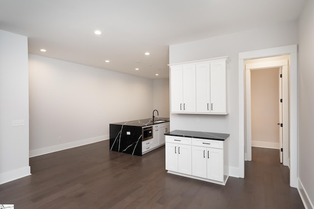 kitchen with white cabinets, appliances with stainless steel finishes, and dark hardwood / wood-style flooring