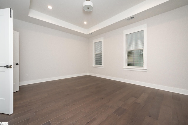 empty room with a raised ceiling and dark hardwood / wood-style floors