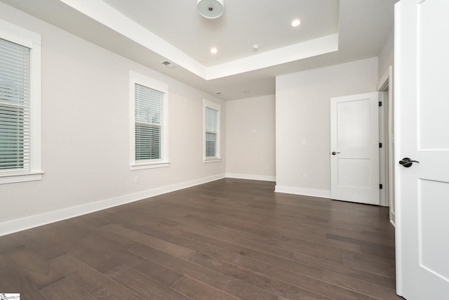 empty room featuring a raised ceiling and dark wood-type flooring