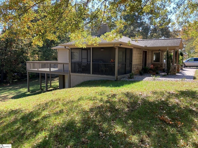 rear view of house featuring a sunroom, a deck, and a yard