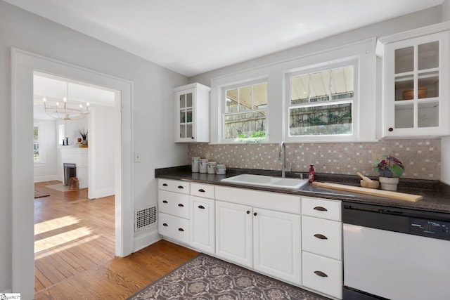 kitchen with light wood-type flooring, white cabinets, tasteful backsplash, sink, and dishwasher