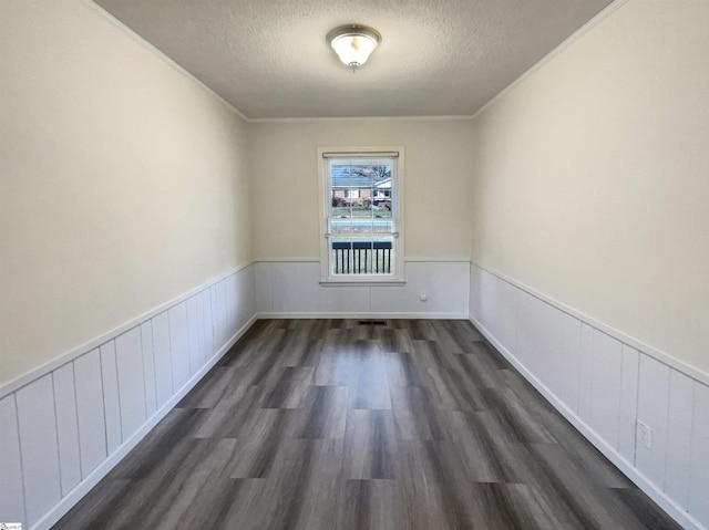 unfurnished room featuring a textured ceiling, dark hardwood / wood-style flooring, and ornamental molding