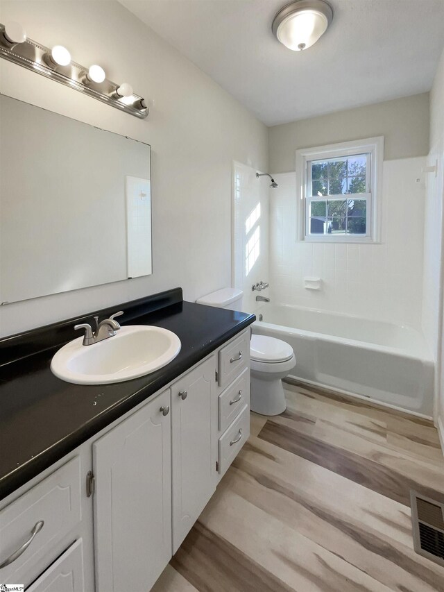 full bathroom featuring wood-type flooring, vanity, toilet, and tiled shower / bath