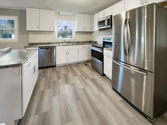 kitchen with white cabinets, sink, light wood-type flooring, and stainless steel appliances