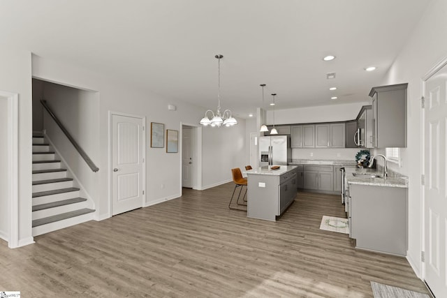 kitchen with decorative light fixtures, a kitchen island, wood-type flooring, and stainless steel appliances