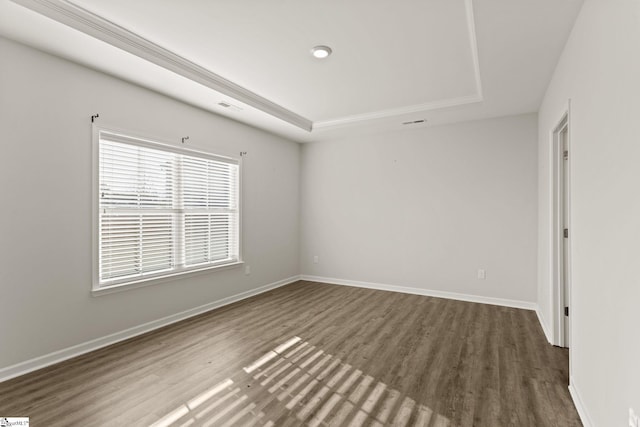 empty room featuring a tray ceiling and dark hardwood / wood-style floors