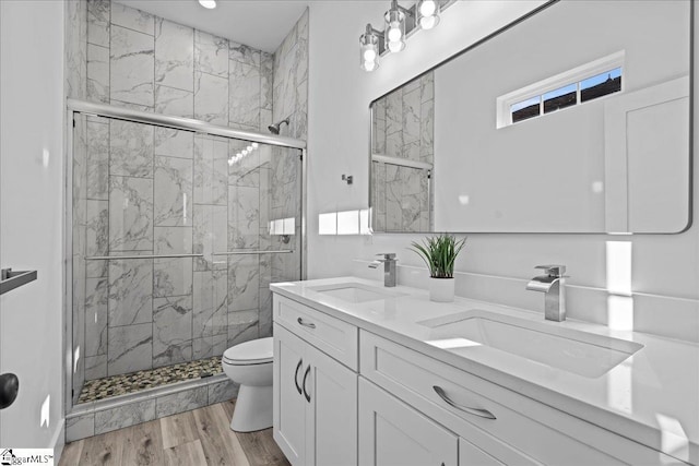 bathroom featuring vanity, hardwood / wood-style flooring, toilet, and a shower with door