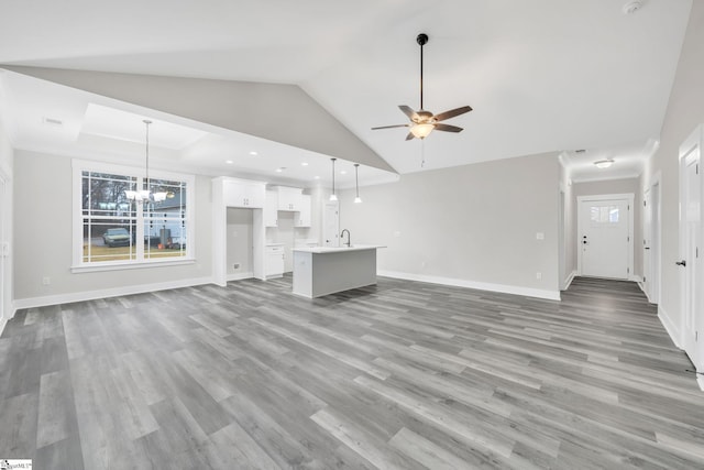 unfurnished living room with ceiling fan with notable chandelier, light hardwood / wood-style floors, lofted ceiling, and sink