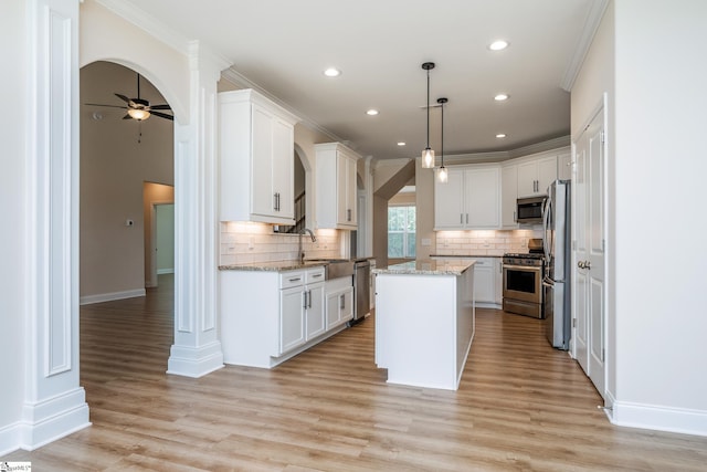 kitchen featuring white cabinetry, appliances with stainless steel finishes, hanging light fixtures, and a kitchen island