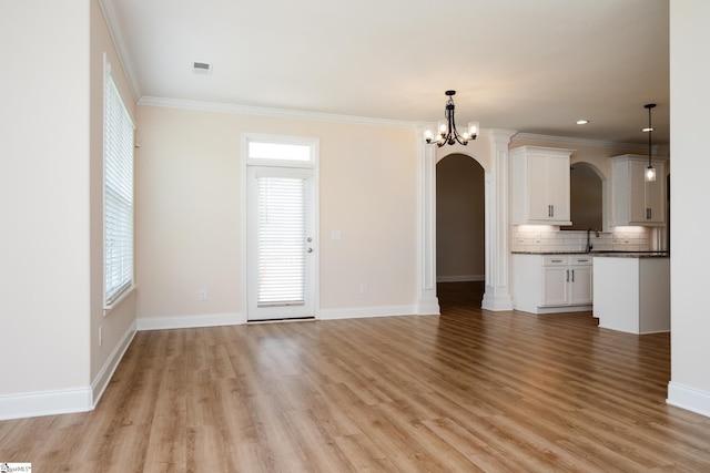 unfurnished living room with ornamental molding, sink, a notable chandelier, and light wood-type flooring