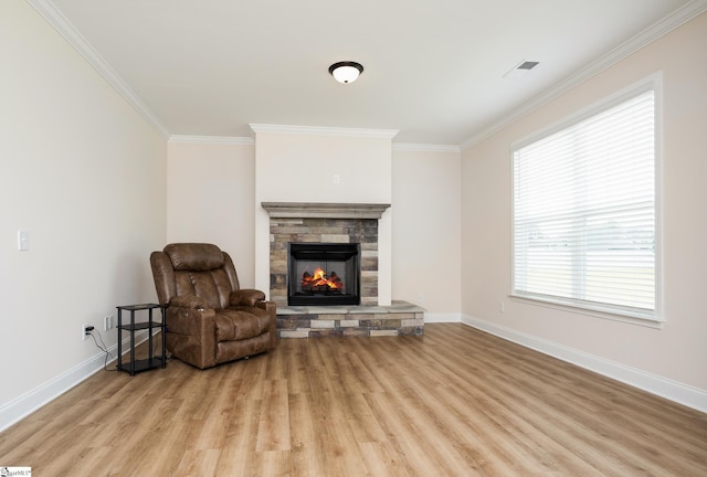 living area featuring a stone fireplace, ornamental molding, and light hardwood / wood-style floors