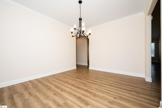 spare room featuring hardwood / wood-style flooring, ornamental molding, and an inviting chandelier