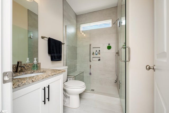 bathroom featuring vanity, toilet, a shower with shower door, and tile patterned flooring