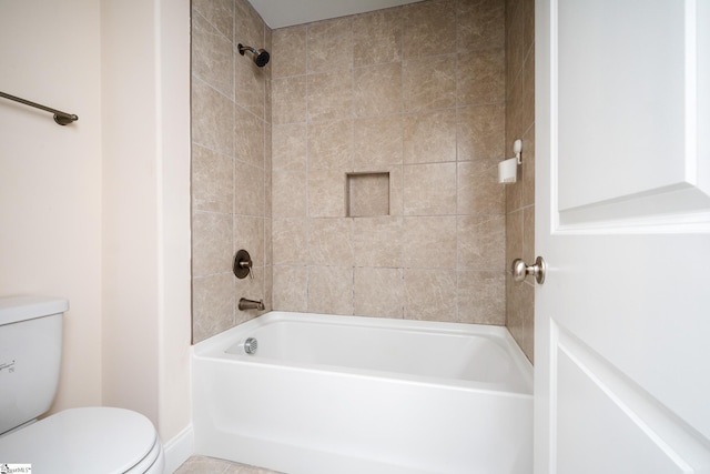 bathroom featuring tiled shower / bath combo and toilet