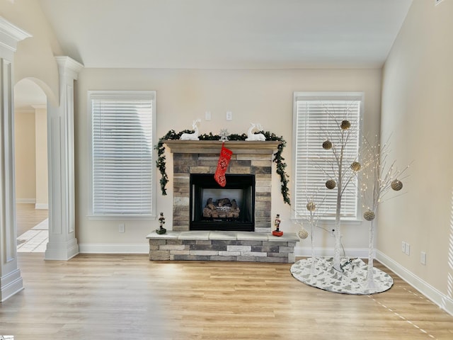 living room featuring a stone fireplace, wood-type flooring, and vaulted ceiling