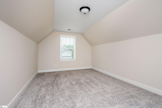 additional living space featuring vaulted ceiling and light carpet