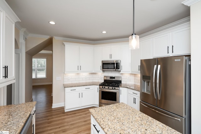 kitchen featuring hanging light fixtures, stainless steel appliances, white cabinets, and light stone countertops