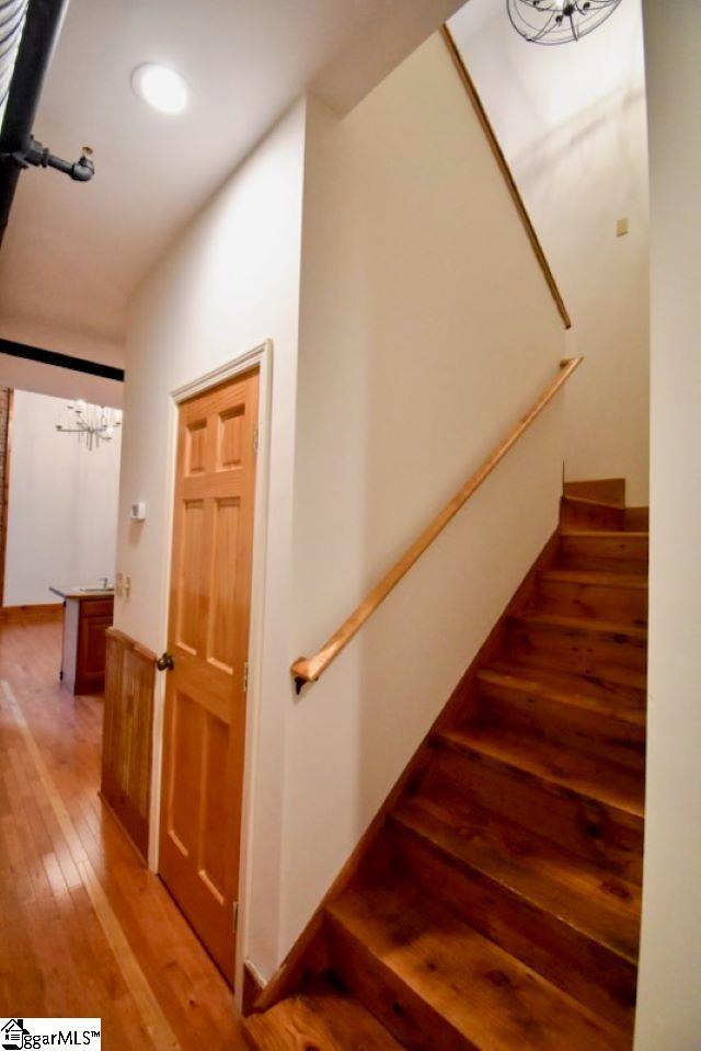 stairway with a notable chandelier and wood-type flooring