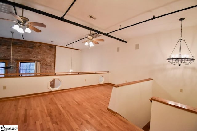 interior space featuring lofted ceiling, light hardwood / wood-style flooring, and ceiling fan with notable chandelier